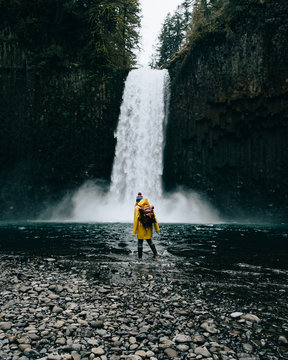 Rear view of woman looking at waterfall in forest