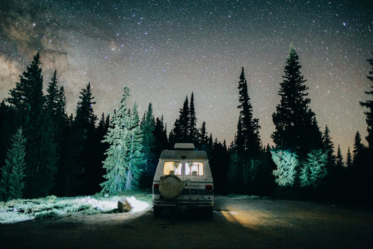 A Van Driving On A Road At Night Under The Stars