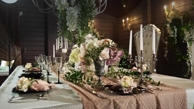 a table set with black arrows with food, wine glasses, flower vases, candlesticks with candles behind which stands two thrones