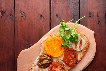 Toast with grilled vegetables. Vegetarian food. Red and yellow tomatoes. Grilled sandwich with tomatoes, onions and herbs. Bread with vegetables and honey. Vegan toast on wooden board