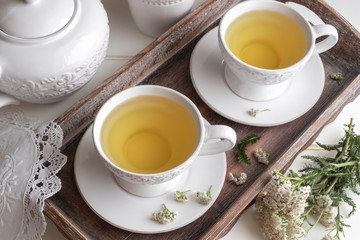 Yarrow tea in white cups with fresh blooming yarrow twigs