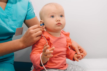 doctor check a baby girl's ears. Little baby having hearing test , procedure impedance audiometry
