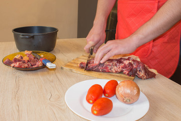 Preparing meal, meat and vegetables. Chef cutting meat on cutting board