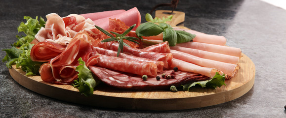 Food tray with delicious salami, pieces of sliced ham, sausage and salad. Meat platter with selection.