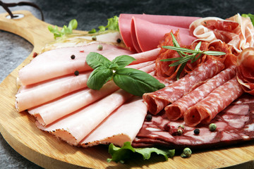 Food tray with delicious salami, pieces of sliced ham, sausage and salad. Meat platter with selection.