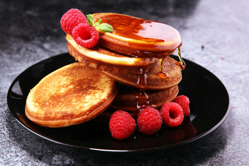 Pancakes with berries and maple syrup on rustic table