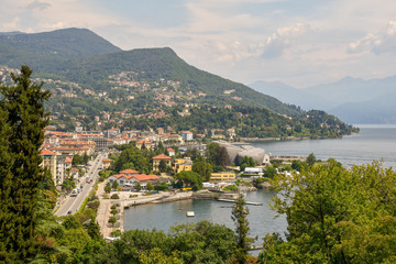 Obraz premium Veduta dall'alto della città di Intra sul Lago Maggiore con montagne sullo sfondo e cielo con nubi, Piemonte, Italia