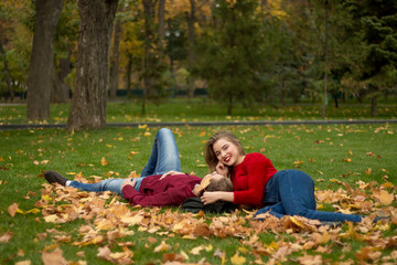 a couple is lying on green grass in yellow maple leaves, their faces are close to each other, a date, lovers, a married couple, an autumn novel, attraction.