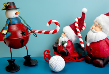 Snowman is playing golf with candy cane as golf club. Two Santa Clauses are watching. Christmas and New Year holiday background concept. Copy space for text.