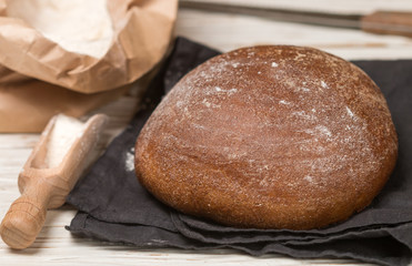 Freshly baked homemade bread, flour and a knife on an old wooden table. Rustic style. Selective focus