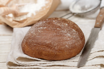 Freshly baked homemade bread, flour and a knife on an old wooden table. Rustic style. Selective focus