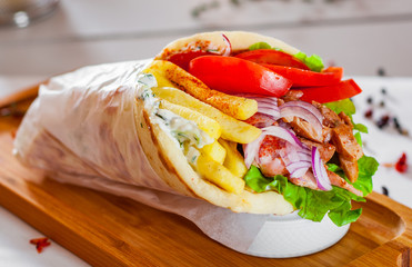 greek lamb meat gyros with tzatziki sauce, vegetables, feta cheese and french fries