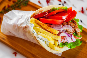 greek lamb meat gyros with tzatziki sauce, vegetables, feta cheese and french fries