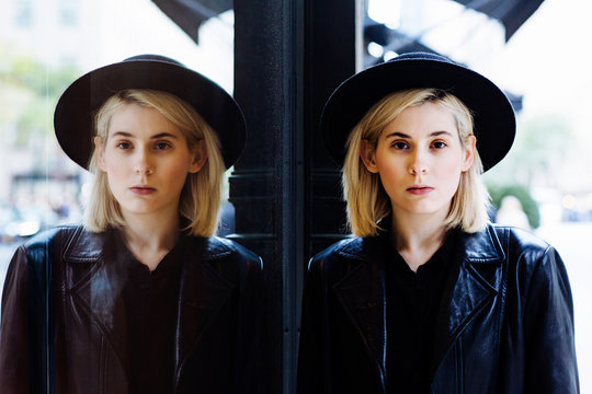 Portrait of a young woman with blonde hair and black hat, standing outdoors