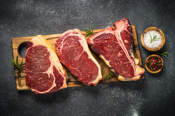 Raw meat beef steak on black top view.