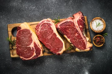 Photo sur Aluminium Viande Steak de boeuf à la viande crue sur la vue de dessus noire.