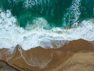 Aerial view of sandy beach with waves and clear ocean water. Drone photo 