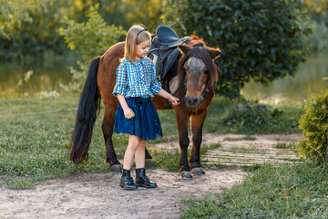A girl and a pony outside at sunset. Nature near the water