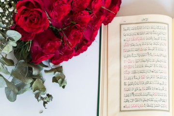Koran and rosary beads on the white background with red roses for Islamic concept. Holy book quran for Muslims holiday, Ramadan,blessed Friday message and three months.