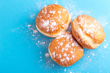 Tasty sweet donuts with powdered sugar on bright blue background