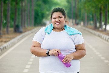 Obese woman holding a bottle on the road