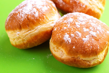Tasty sweet donuts with powdered sugar on bright green background