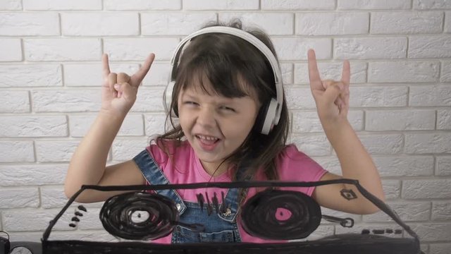 The child plays a DJ. Girl with an imaginary DJ console. Drawing on glass