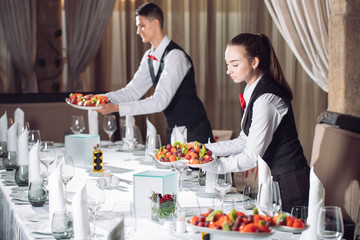 Waiters serving table in the restaurant preparing to receive guests.