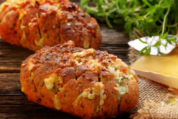 Garlic bread with cheese and herbs on wooden background