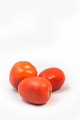 Three bright red plum Roma tomatoes against a white background