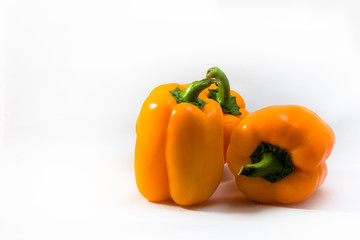 Three fresh orange yellow peppers against a white background