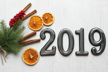 Fototapeta na wymiar Date 2019 on white wooden background, fir branches, cinnamon sticks and dried orange slices, bokeh effect. 2019 New year.Volume Numbers, dates 2019 on white wooden background, fir-tree branches, bokeh