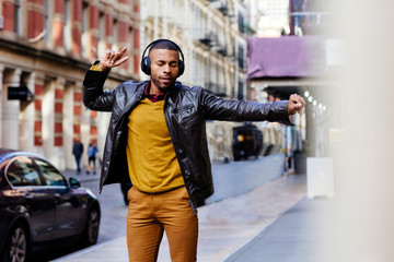 Portrait of a cool young man enjoying and dancing to music in the street