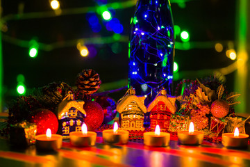 Merry Cristmas. Toy houses and candlelight. Christmas decorations on blurred background. Festive evening. Spruce branches and Christmas toys with bokeh. Copy space