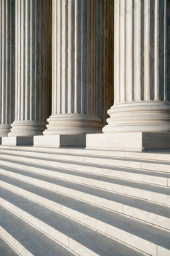 Abstract close-up of the neoclassical white marble fluted columns with steps at the entrance to the US Supreme Court Building in Washington DC