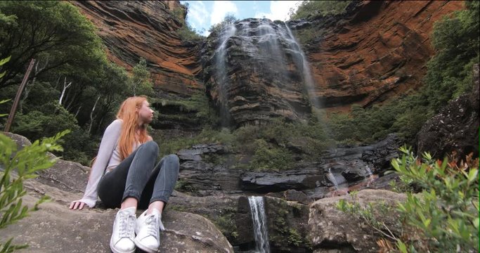 Young Woman Sits Underneath Large Wentworth Waterfall. Young Girl Discovering He