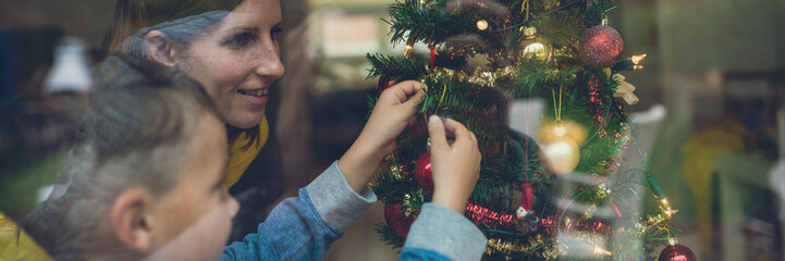 Wide view image of mother and son decorating Christmas tree