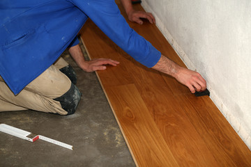Worker laying parquet flooring. Worker installing wooden laminate flooring.