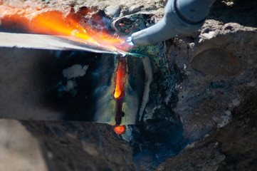 Cutting torch cutting metal bar, flame, hot.