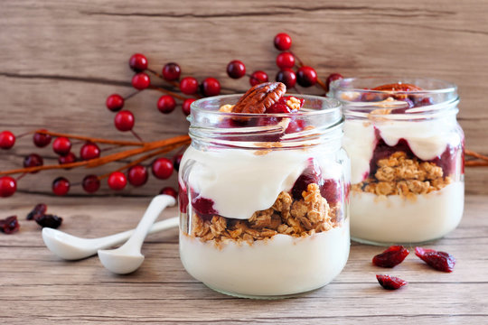 Cranberry granola parfaits in mason jars on a rustic wood background