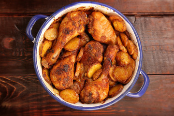Roasted chicken drumstick with potatoes and salad on wooden background