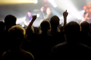 Silhouettes of concert crowd against bright stage lights