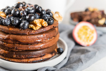Stack of homemade chocolate pancakes with blueberries and chocol