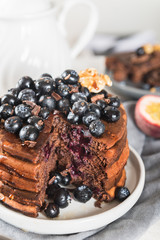 Stack of homemade chocolate pancakes with blueberries and chocol