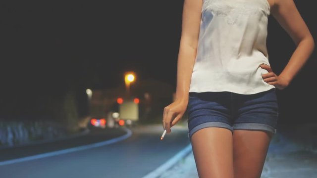 Prostitute with cigarette waiting for the client at night street.