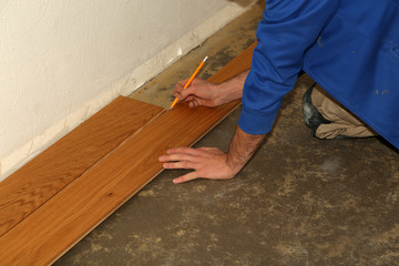 Worker laying parquet flooring. Worker installing wooden laminate flooring.
