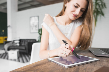 Young business woman working at home and draws on the tablet. Creative Scandinavian style workspace