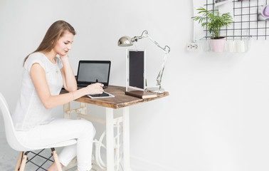 Young business woman working at home and draws on the tablet. Creative Scandinavian style workspace