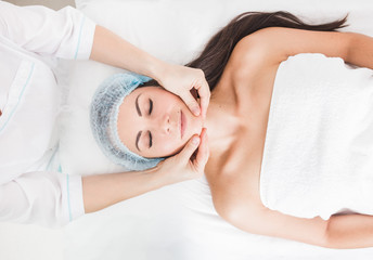 Young beautiful girl getting a facial massage in a beauty salon