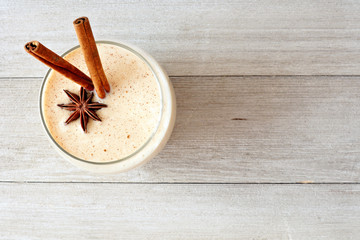 Christmas spiced eggnog in a glass. Top view on a rustic gray wood background.